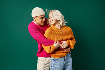 cheerful couple in winter attire having fun, man in beanie hugging girlfriend on turquoise backdrop