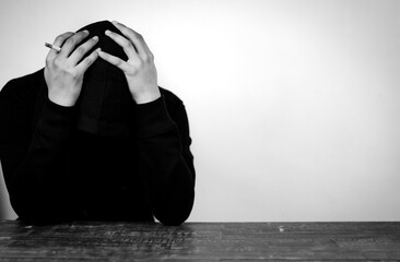 Portrait of Depressed Man wearing black hoodie hiding his face with hands. Stressed, Hopeless,...