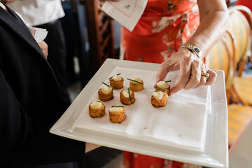 arm of caucasian woman in coral dress reaching for crab cake canape at elegant wedding
