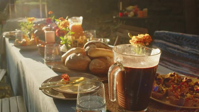 No people lens flares shot of beautifully set dining table with fresh bread, candles and marigold flowers in vases in autumn backyard on sunny day