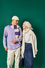 stylish couple in winter attire, happy woman posing with man in warm clothing on turquoise backdrop