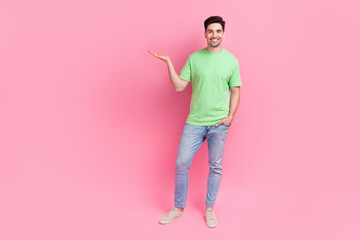 Full body photo of man wear casual green clothes produce content for marketing agency hold hand product isolated on pink color background