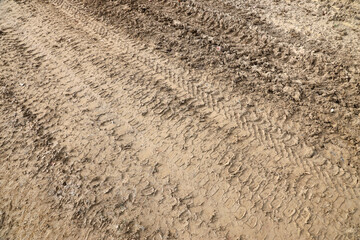 Wheel track on mud. Traces of a tractor or heavy off-road car on brown mud in a wet meadow