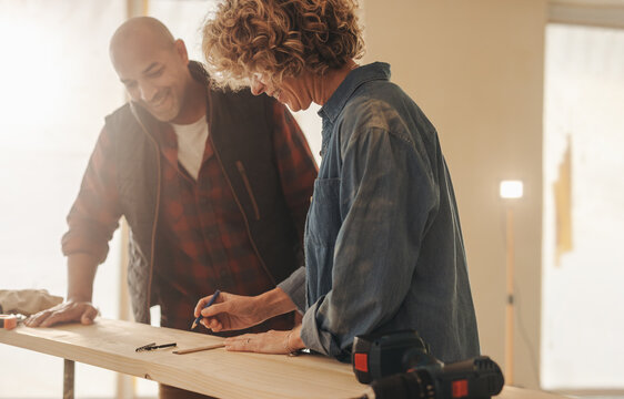 Homeowners discussing renovation project with tape measure and plank