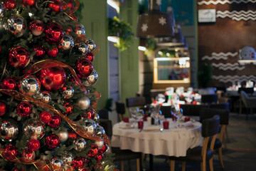 Christmas, New Year red restaurant interior with decorated fur-tree, tables and chairs.