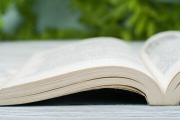 Open hardback book, on wooden table. natural background . Back to school. Copy space for text.