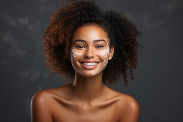 Close-up of young African American woman with moisturizer on her face. Smiling face of beautiful...