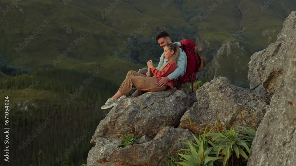 Poster Hiking, mountain and love, couple relax on outdoor adventure and peace in nature with romance. Trekking, rock climbing and view, man and woman with view of natural landscape sitting on cliff together