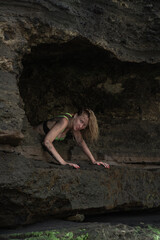 Sexy girl in green underwear posing against the background of rocks smeared with volcanic sand