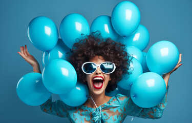 Overjoyed fashionable woman has fun on party covers face with palm dressed in stylish holds bunch of inflated balloons enjoys festive celebration isolated over blue background - obrazy, fototapety, plakaty
