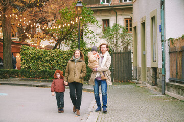 Fototapeta premium Family of four walking down the street, young couple with little children outside , fall time