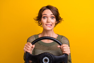 Photo portrait of pretty young girl hold steering wheel excited wear trendy knitwear khaki outfit isolated on yellow color background