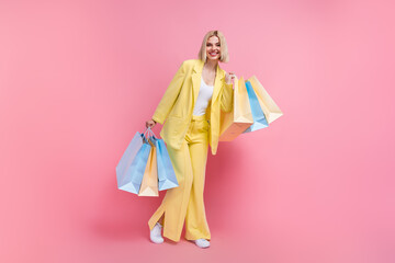Full body portrait of positive stunning young lady hold store mall bags wear classy costume isolated on pink color background