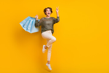 Fototapeta na wymiar Photo of positive cheerful girl wear trendy clothes showing v-sign flying air empty space isolated on yellow color background