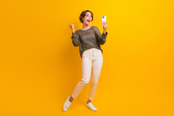 Fototapeta na wymiar Full length photo of overjoyed glad blogger girl dressed stylish outfit talking online live stream isolated on yellow color background