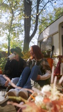 In true hippie fashion, cheerful and lively girls revel in tea and conversation in the beautiful autumn garden near the trailer.