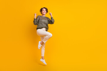 Fototapeta na wymiar Photo of excited cheerful cool girl dressed stylish clothes celebrate success jumping up empty space isolated on yellow color background