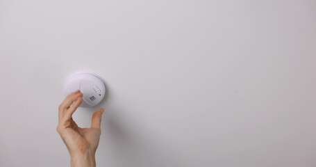 hand installing photoelectric smoke detector on house ceiling. home security, fire alarm system