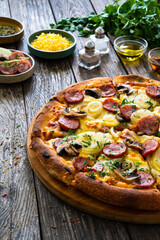 Circle pizza with sausages, onion and mozzarella cheese on wooden table
