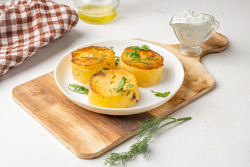 Potato fondant, a delicious potato dish sprinkled with herbs in a white plate on a wooden board.
