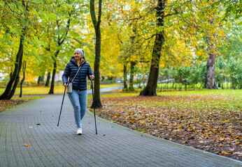 Nordic walking - mid-adult woman exercising in city park
