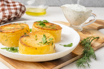 Potato fondant, tender potatoes with pucks close-up in a white plate.