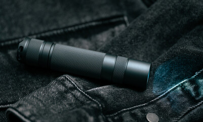 Pocket flashlight for Everyday Carry (EDC) on a dark background. Ray of light.	