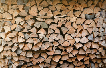 Firewood stacked near the wooden wall of old hut. Many chopped logs of firewood close up