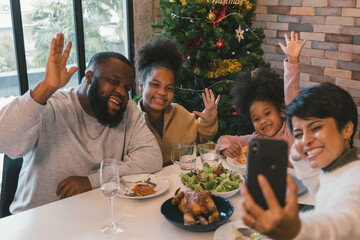 Cheerful african american family enjoying christmas and new years lunch while woman taking selfie...