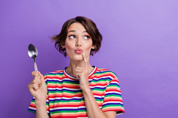 Photo of cute mined girl wear trendy striped clothes hand hold spoon face chin choose meal empty space isolated on purple color background