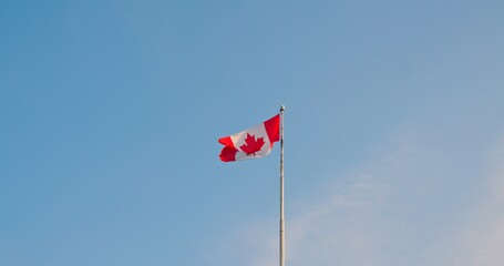 National flag of Canada also known as The Maple Leaf. Red white flag of Canada fluttering in breeze. Slow motion bottom view of Canadian flag high in sky. Enjoy atmosphere of Canada and Canadian life