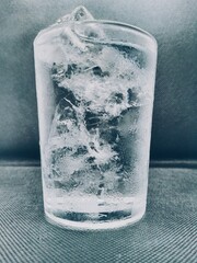 Glass of water with ice cubes, water drops around the glass, cool temperature