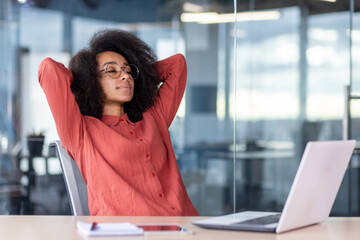 Young beautiful woman resting in the office, business woman with hands behind her head, dozing and...