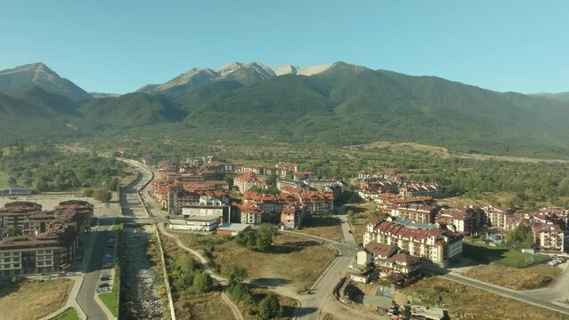 Aerial shot, flying towards Pirin Mountains from the edge of Bansko mountain resort.
