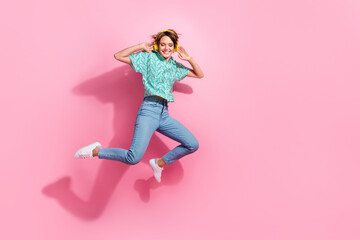 Full size portrait of excited nice girl jump hands touch headphones empty space isolated on pink color background