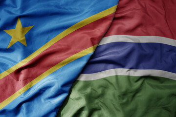 big waving national colorful flag of democratic republic of the congo and national flag of gambia .