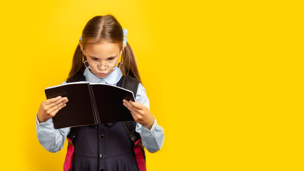Schoolgirl holding books ready for Back To School standing in studio on yellow background. School Education Concept.