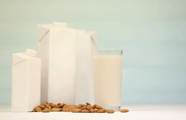 Glass of almond milk with almond nuts on canvas fabric on white wooden table. Dairy alternative milk for detox, healthy eating and diets. Selective focus