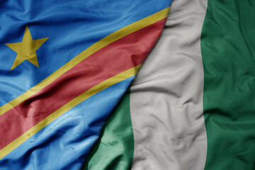 big waving national colorful flag of democratic republic of the congo and national flag of nigeria .