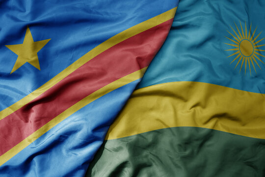 big waving national colorful flag of democratic republic of the congo and national flag of rwanda .