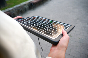Top view of woman holding portable solar panel with reflected sunlight. Close up view of woman...