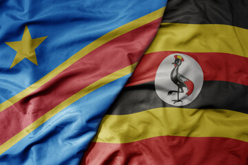 big waving national colorful flag of democratic republic of the congo and national flag of uganda .