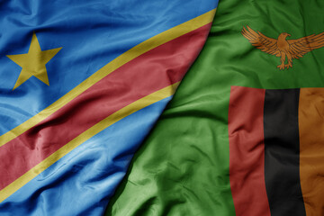 big waving national colorful flag of democratic republic of the congo and national flag of zambia .