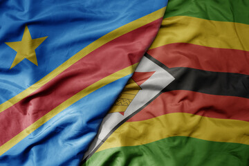 big waving national colorful flag of democratic republic of the congo and national flag of zimbabwe .