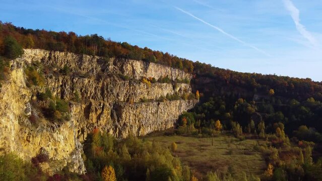 Drone flying over abandoned quarry in autumn with colorful lead tree foliage