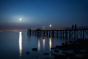 Fototapeta na wymiar Against the gentle lull of waves, fishermen on a timeworn pier harness the moon's radiant glow tradition with nature's rhythm.
