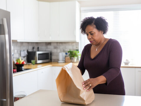 A woman opens shopping bags in the kitchen