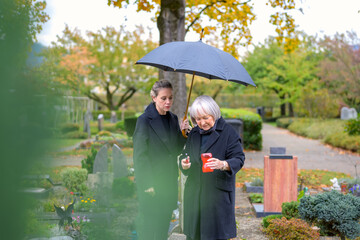 Mother and her daughter-in-law try to light a candle at her son's grave
