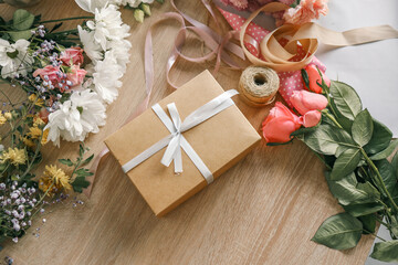 Gift box in hands with flowers at home