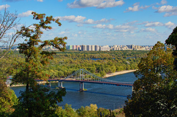 Aerial landscape view of River Dnipro with Pedestrian bridge. It connects the central part of Kyiv with the park area and the beaches of Trukhanov Island. Built in 1956-1957. Skyscrapers on horizon